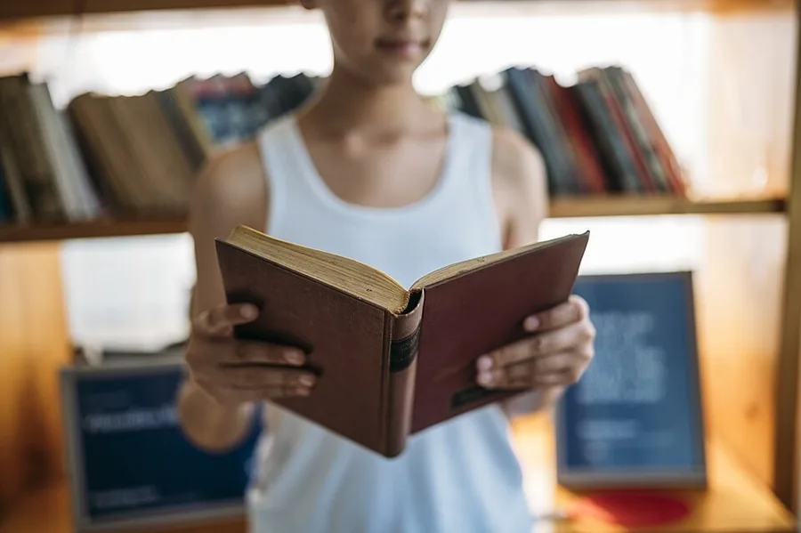 Человек читает книгу у окна