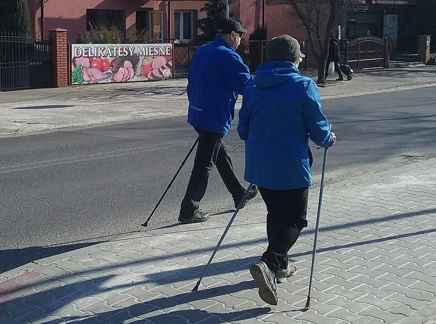 Пожилая пара занимается скандинавской ходьбой
